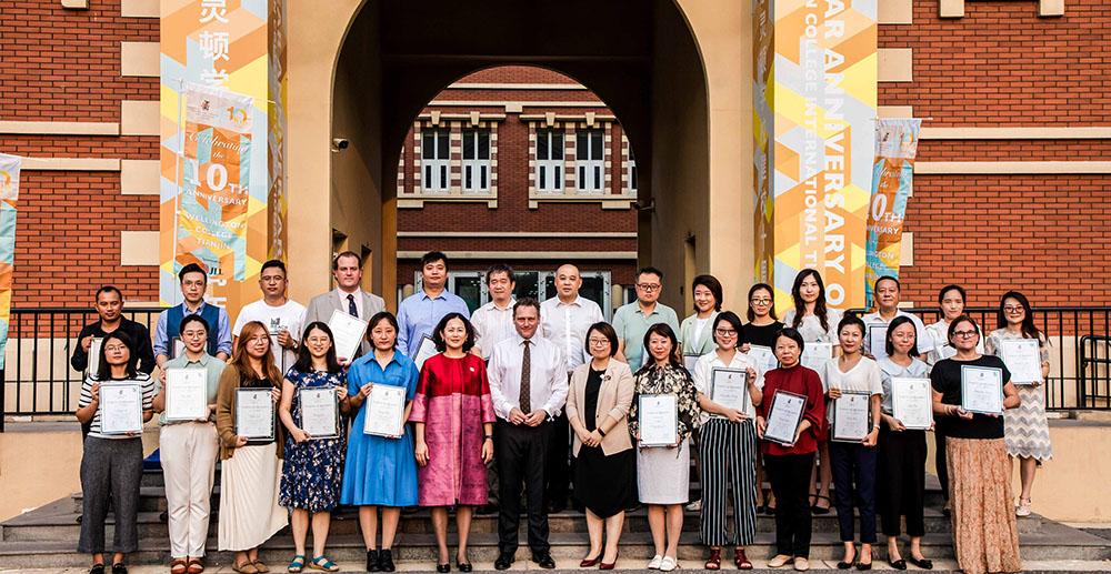 A group of teachers pose for a photo while holding certificates at Hiba Academy Bay Area, an international school in San Francisco.