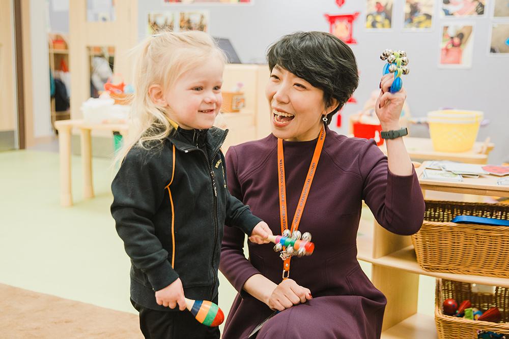 A teacher encourages a young student to express herself, representing the importance of addressing the needs of the whole child and integrating language development into the curriculum.