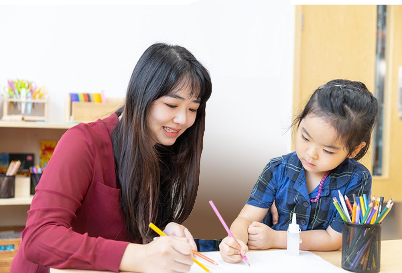 A teacher at Hiba Academy Bay Area, an independent school in San Francisco Bay Area, colouring on paper with a pupil as part of the Early Years curriculum.