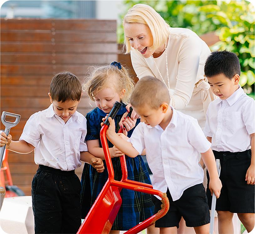 A teacher guiding a group of young children as they explore gardening tools at Hiba Academy Bay Area, a private school in San Francisco Bay Area that focuses on educating the whole child.