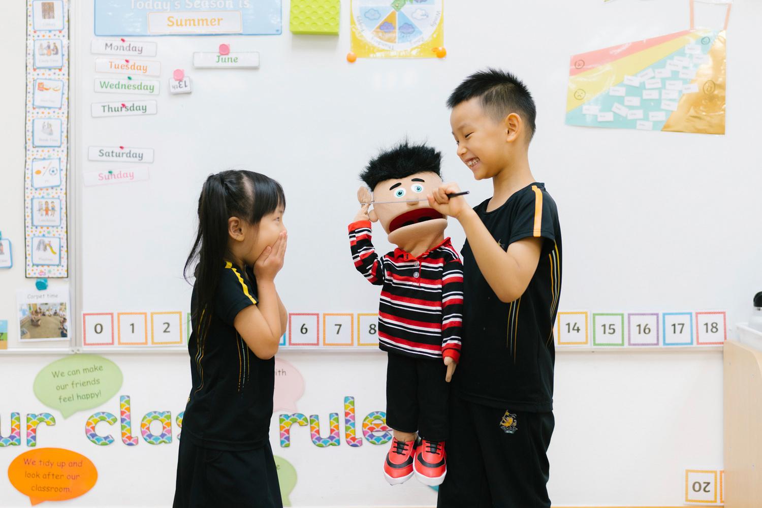 Two students perform a skit with a puppet, showcasing how Hiba Academy’s holistic curriculum addresses the needs of the whole student.