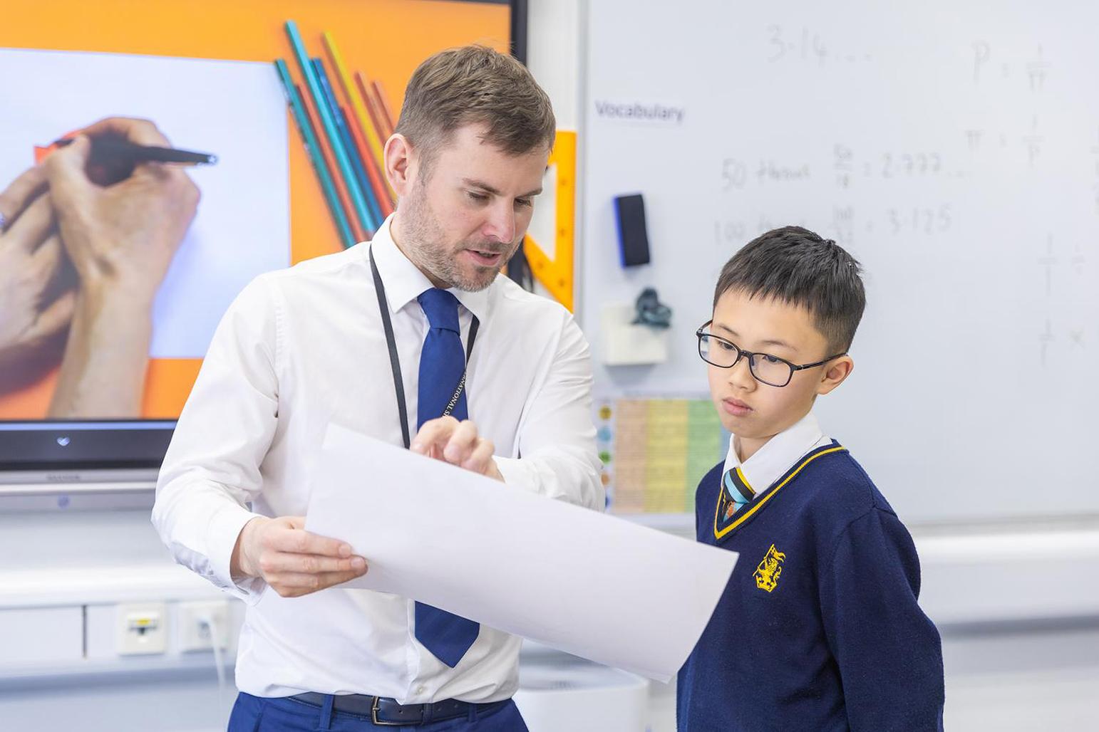 A teacher explains a concept to a primary school student on a paper at Hiba Academy Bay Area, a dual-language international primary school with International Baccalaureate, International Primary Curriculum, and social and emotional learning programs.