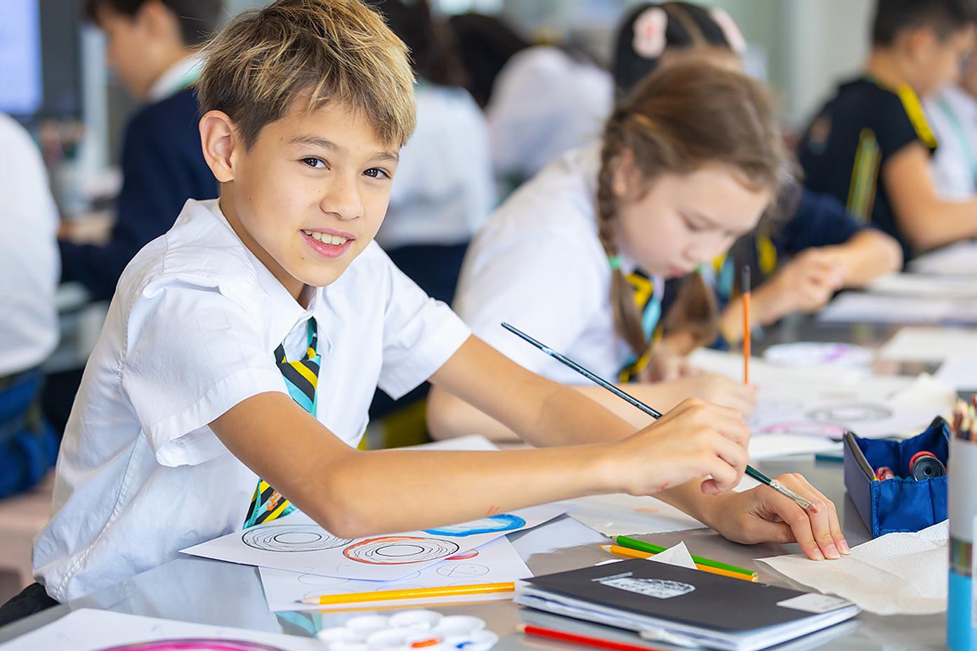 A boy in Hiba Academy Bay Area uniform paints in class, showcasing the private school’s holistic curriculum that is based on the International Baccalaureate (IB) Primary Years Program.